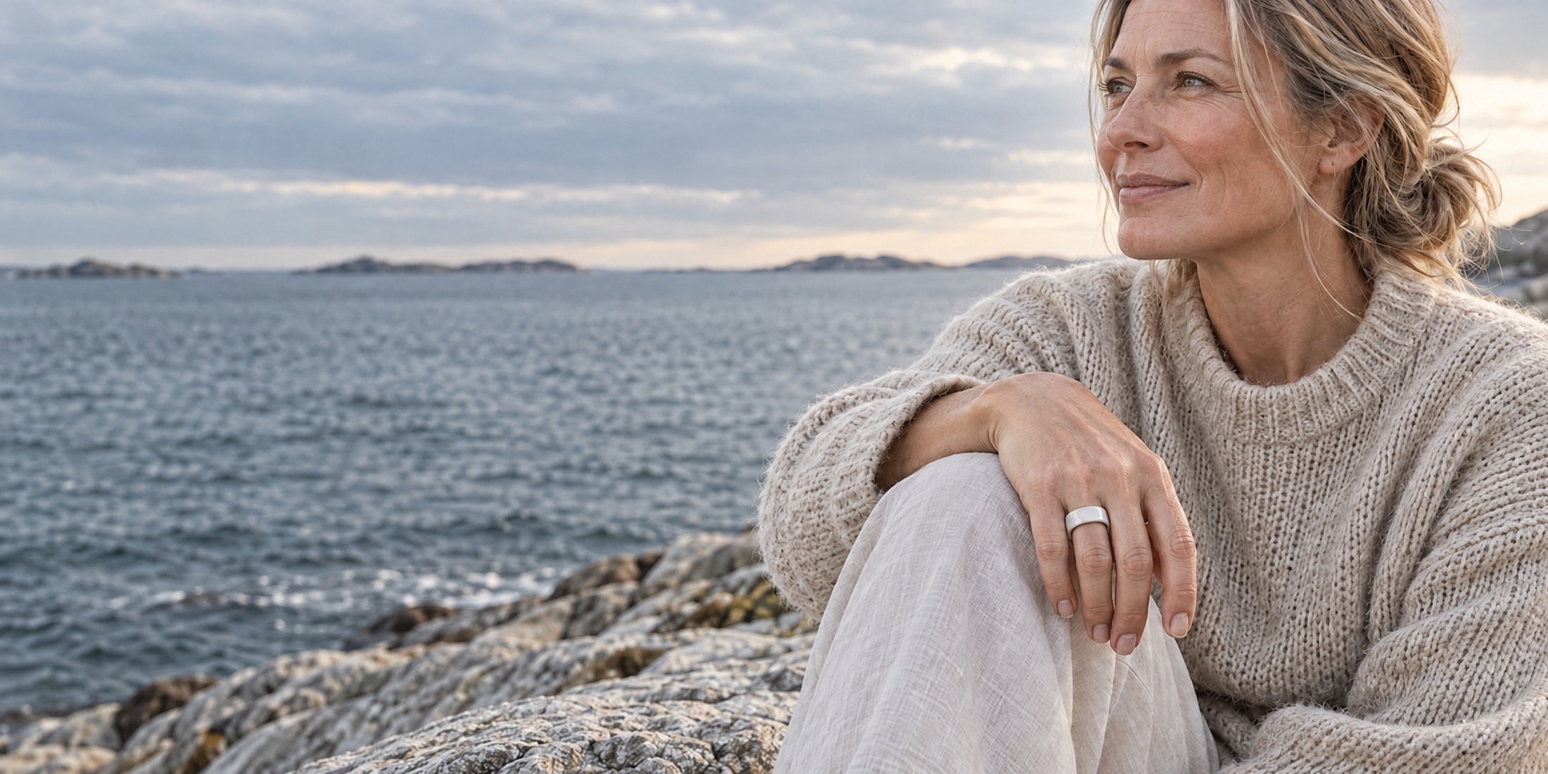 A woman on the Scandinavian coast wears a white ceramic ring. AI-created scene based on the product reference.